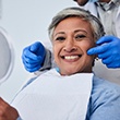Woman smiling while holding handheld mirror with dentist