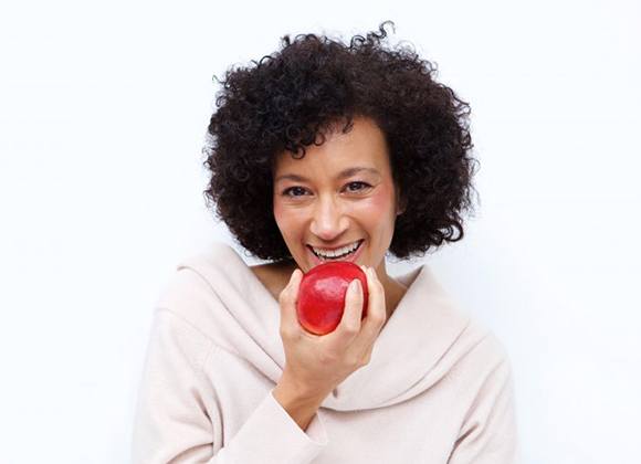 smiling woman biting into a red apple