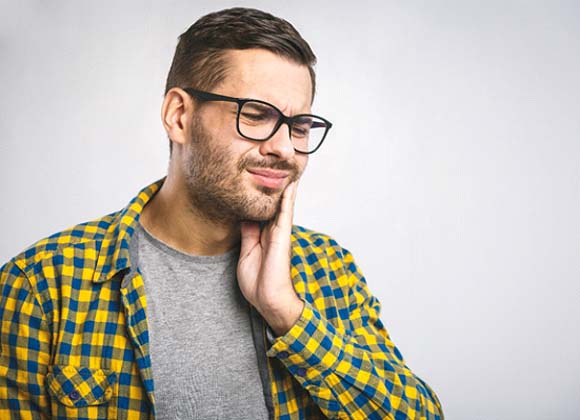 Man with a toothache in Waverly holding his cheek