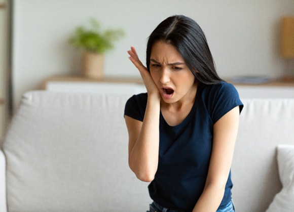 a woman holding her cheek due to a dental emergency