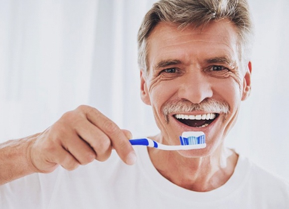 older man in white t-shirt brushing his teeth for gum disease prevention in Waverly