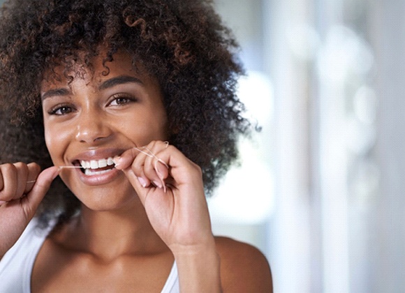 young woman smiling and flossing