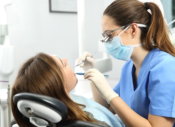 dental hygienist cleaning patient’s teeth