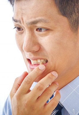 Man checking his gums in small mirror