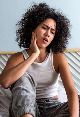 Woman rubbing her jaw at home