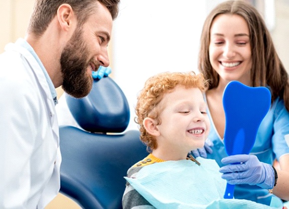 little boy smiling in dental chair after pulp therapy in Waverly 