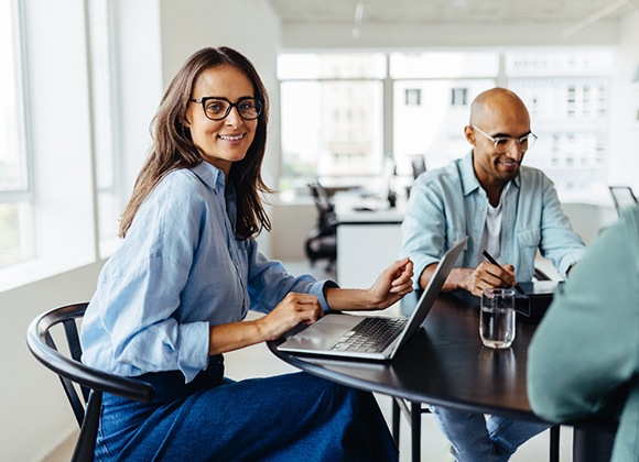 Woman smiling with colleagues while working on computer