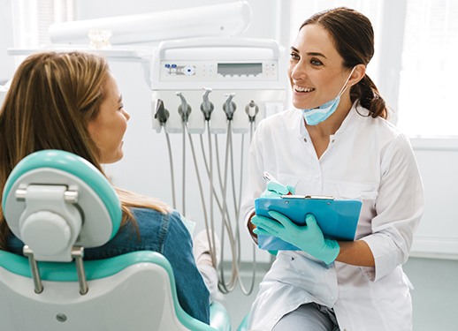 Dentist smiling at patient while taking notes on clipboard