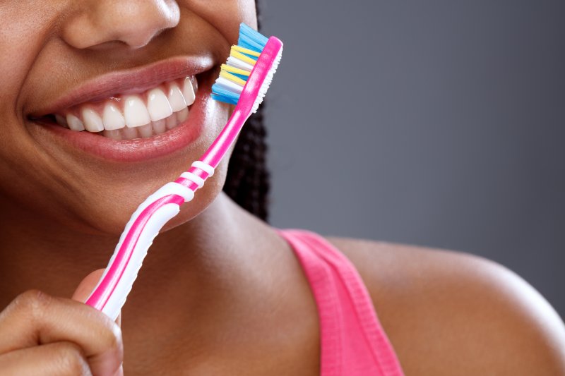 a young woman smiling and holding a manual toothbrush 