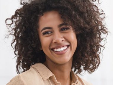 smiling woman with implant dentures in Waverly