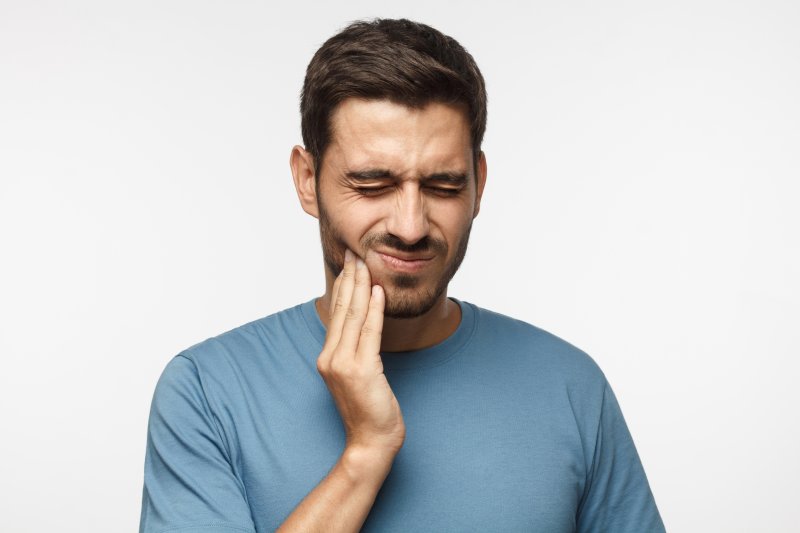 Man having a dental emergency, touching his cheek