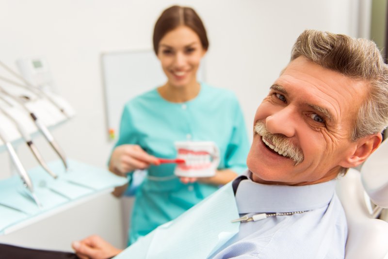 An older man smiling after getting his dentures