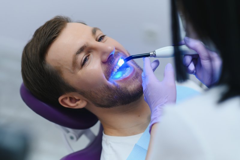 A closeup of a bearded man receiving a dental filling