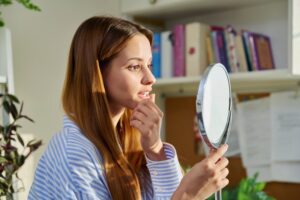 Woman looking at her dental implant in a mirror
