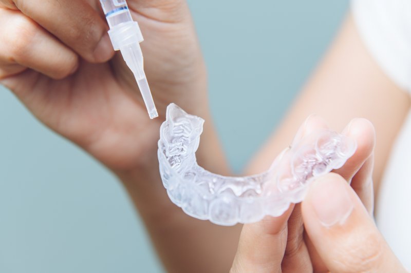 A patient holding a tooth whitening mold and whitening gel